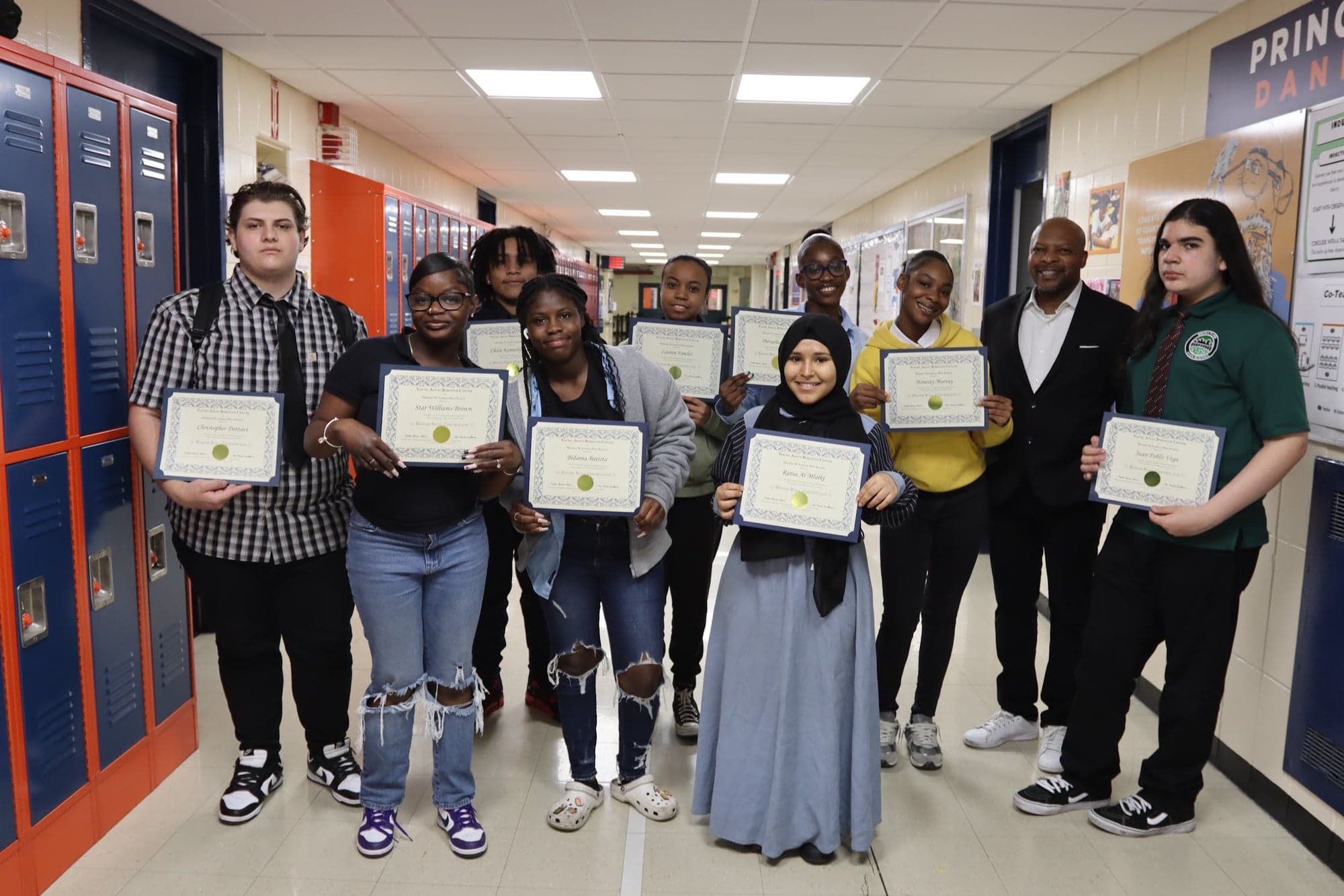 Martin Smallhorne with honor roll students holding their certificates in a school hallway